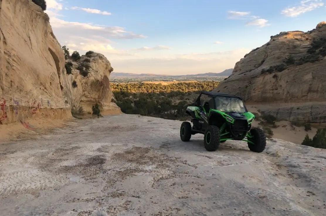 Side-by-side UTV beside a slickrock canyon vista on a guided tour near Vernal Utah