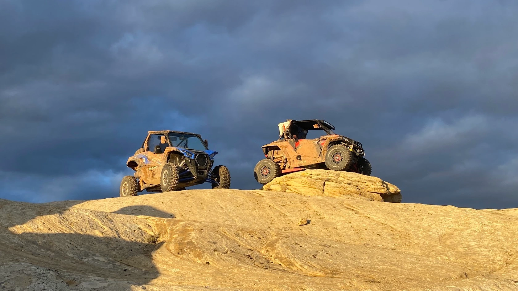 Riders standing atop slickrock beside their Kawasaki KRX 1000 side-by-sides near Vernal Utah