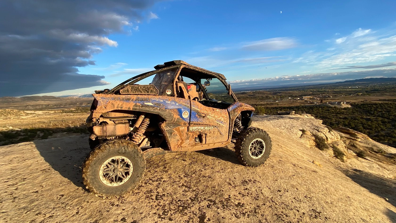 Muddy side-by-side UTV on a rock dome at an overlook near Vernal Utah