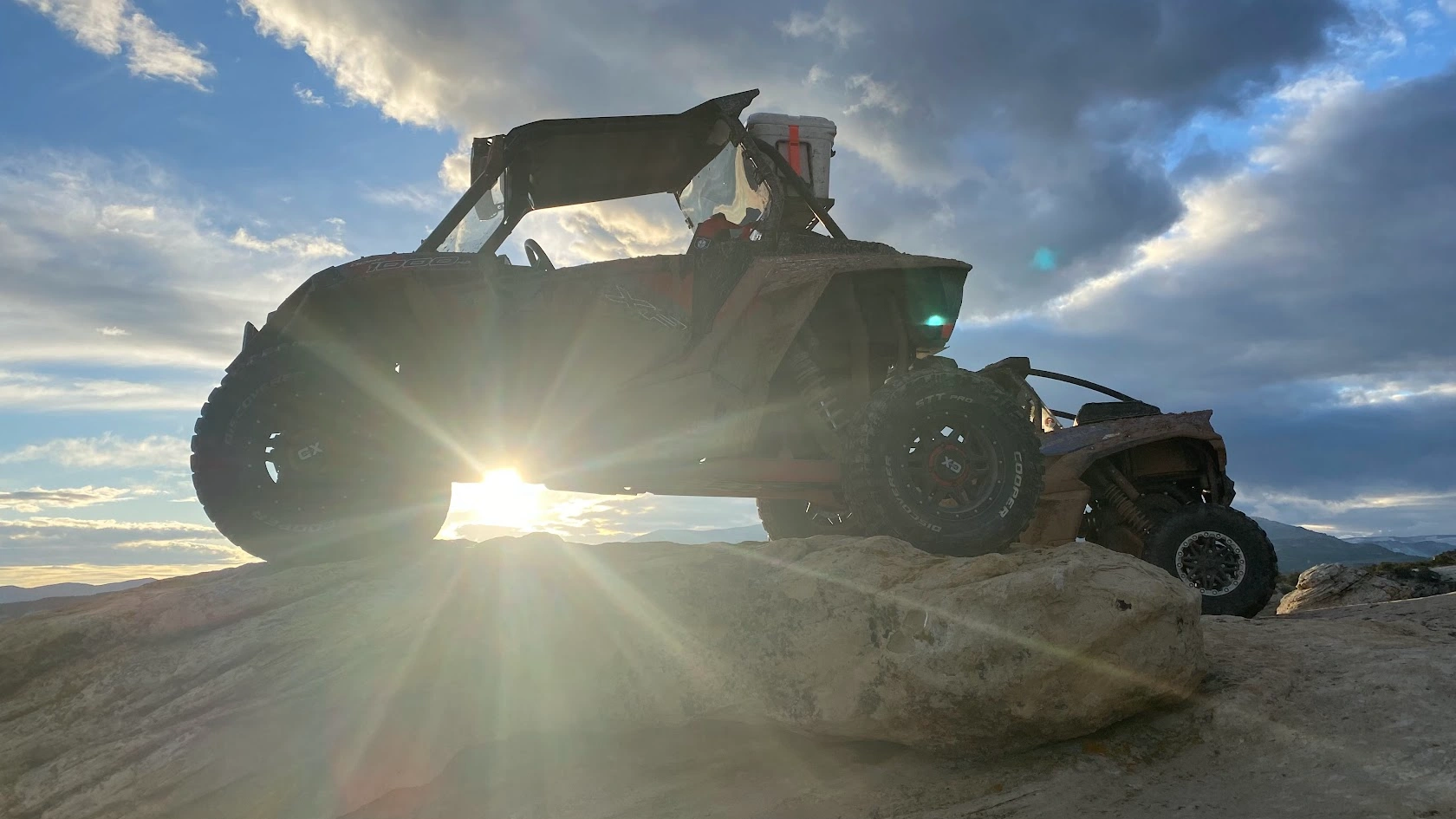Side-by-side UTV silhouetted against a sunburst on a sunset ride through the Utah desert backcountry