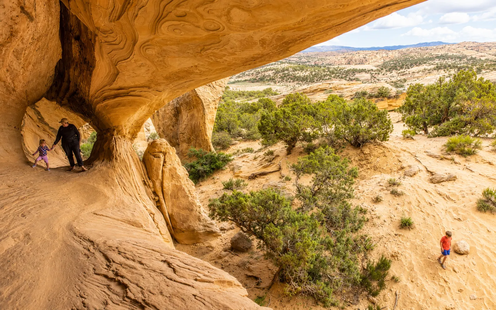 Hikers exploring a sandstone arch on an Adventure Tours Vernal outing in Vernal Utah