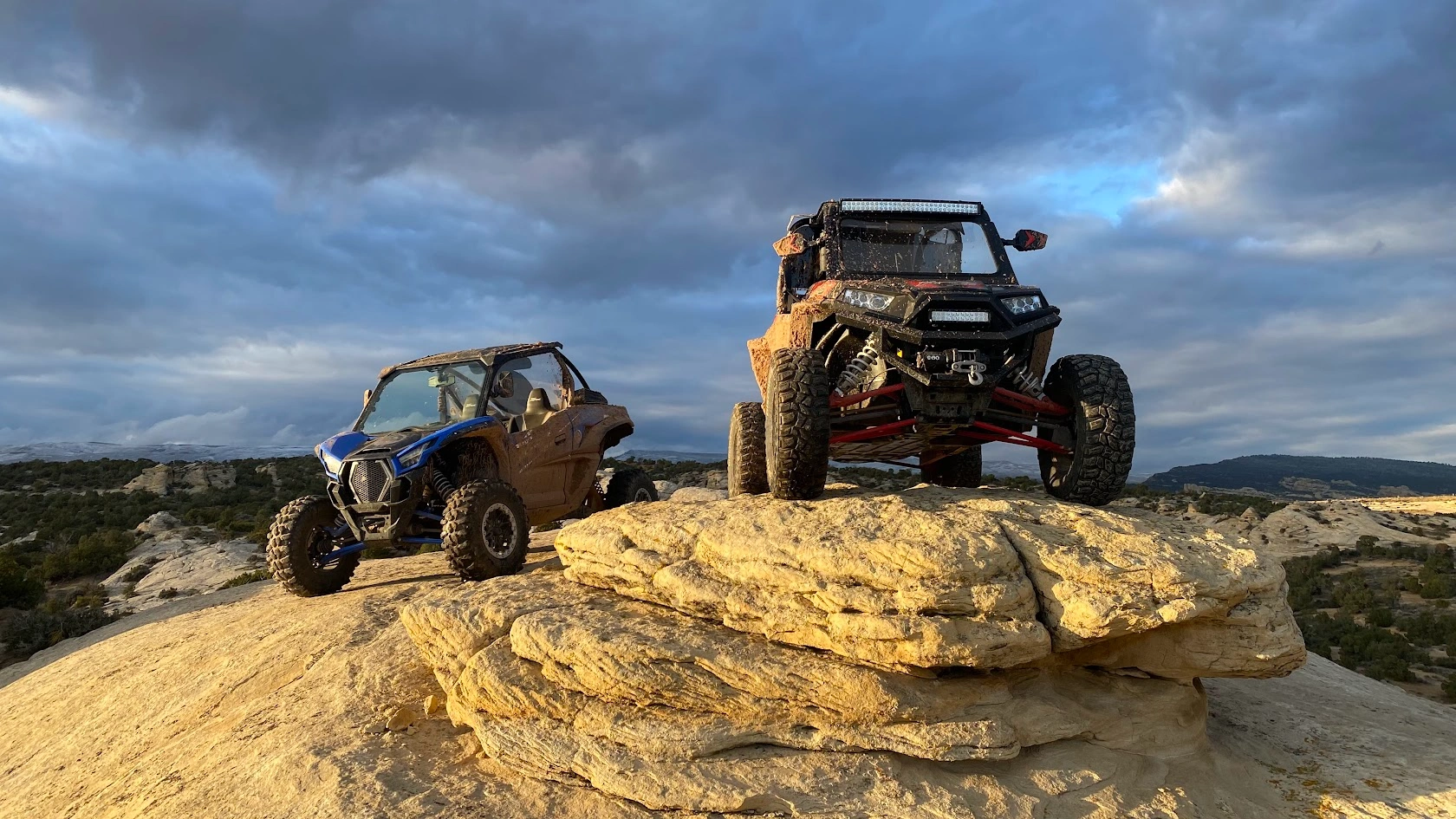 Two side-by-side UTVs perched on a boulder on a backcountry tour near Vernal Utah