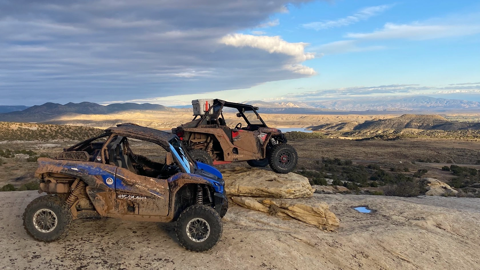 Muddy side-by-side UTVs overlooking the valley on a backcountry trail near Vernal Utah
