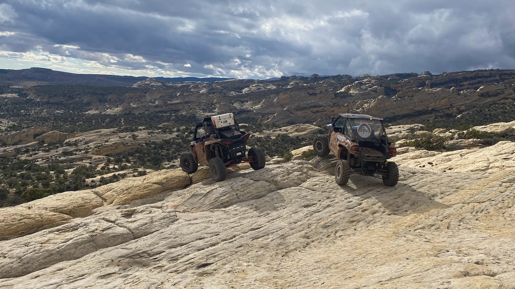 Side-by-side UTVs climbing a sandstone ridge near Vernal Utah
