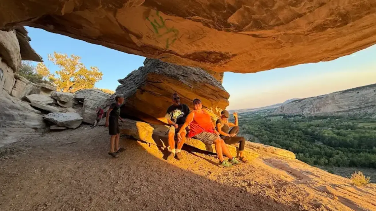 Riders resting under a sandstone overhang at sunset on an Adventure Tours Vernal UTV tour