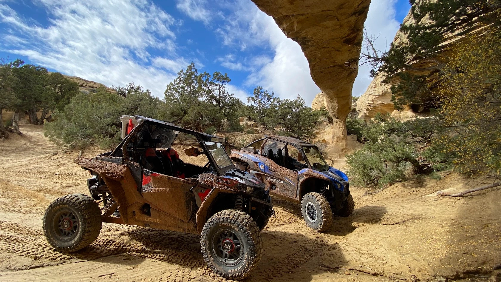 Side-by-side UTVs parked under a natural rock arch near Vernal Utah
