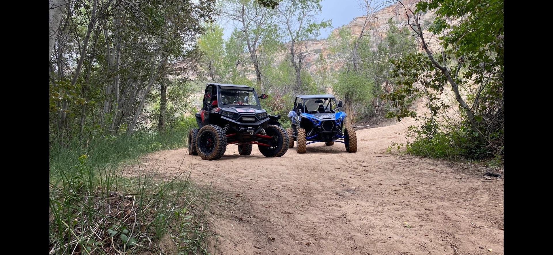 Two side-by-side UTVs on a canyon trail through the Utah backcountry