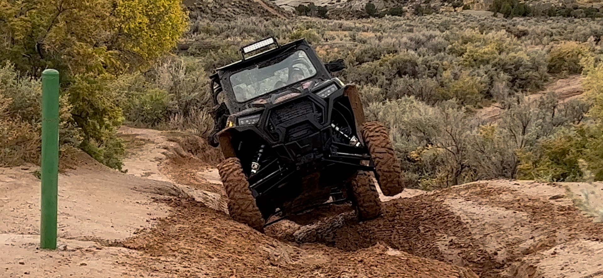 Side-by-side UTV tackling a deep rut on a backcountry trail near Vernal Utah