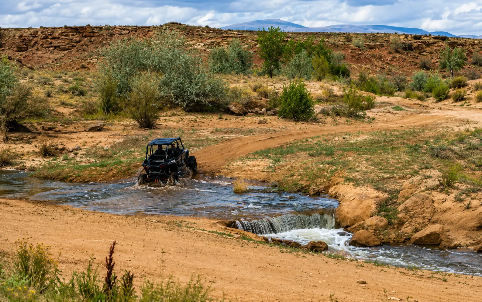 Side-by-side UTV splashing through a river crossing near Vernal Utah