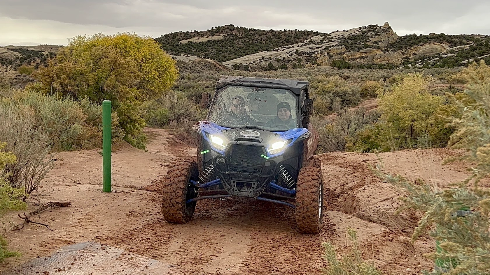 Side-by-side UTV charging through a muddy backcountry trail near Vernal Utah