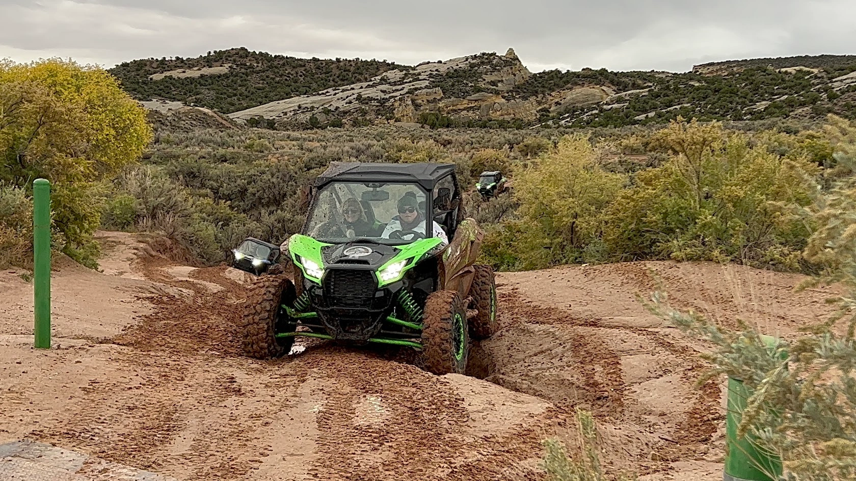 Green Kawasaki side-by-side UTV crossing a muddy rut near Vernal Utah