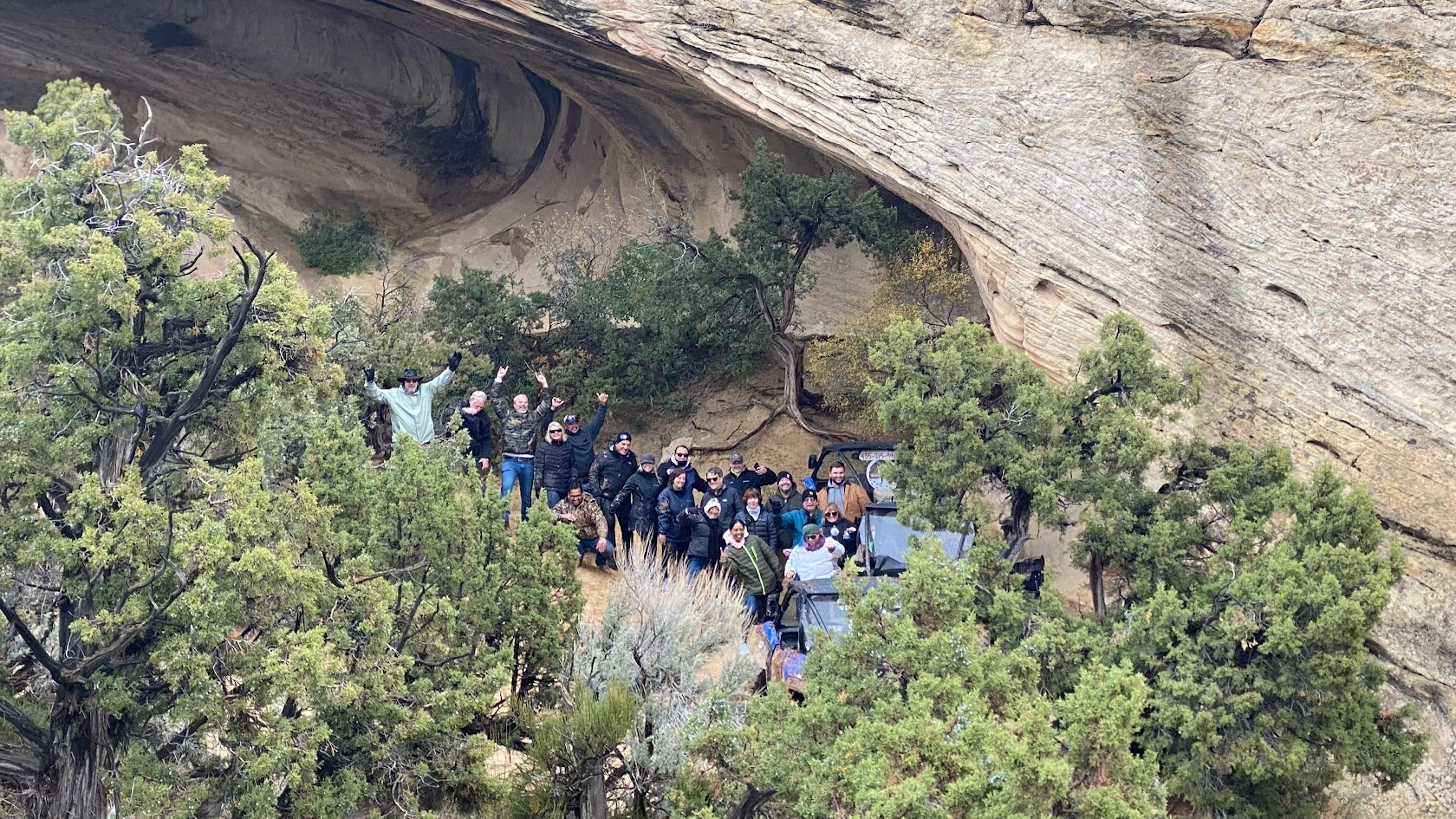 Tour group gathered under a rock overhang with their side-by-side UTVs near Vernal Utah