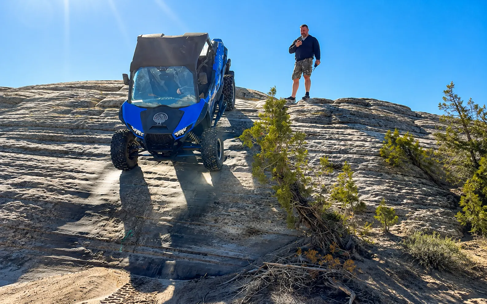 Blue side-by-side UTV conquering a slickrock dome with a guide near Vernal Utah