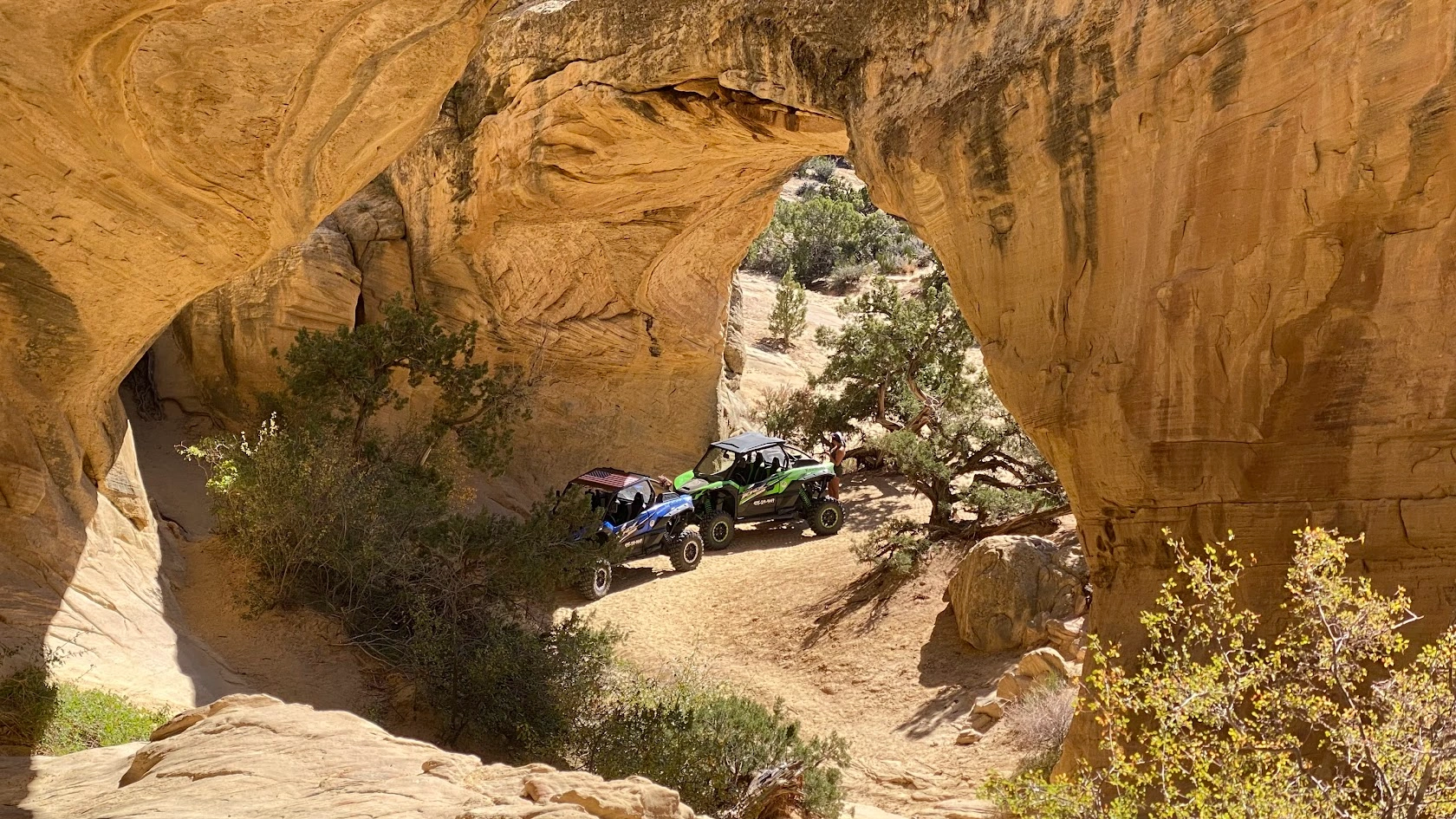 Side-by-side UTVs parked under a sandstone arch near Vernal Utah