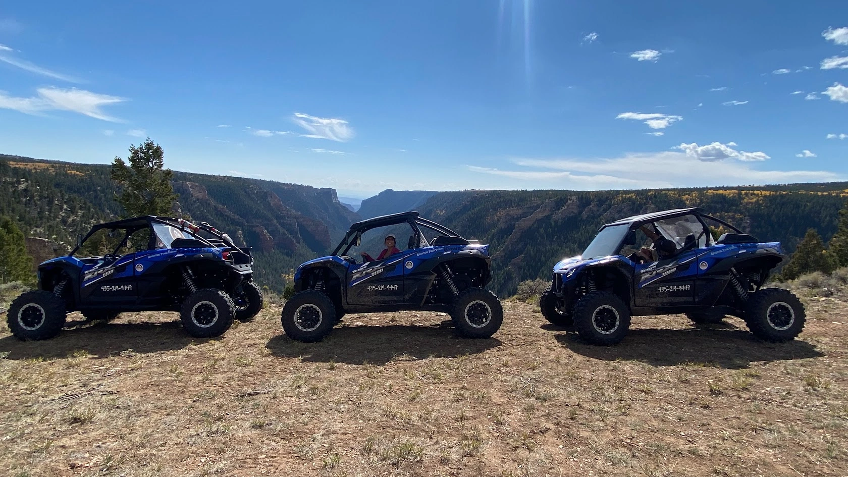 Three side-by-side UTVs on the canyon rim near Vernal Utah