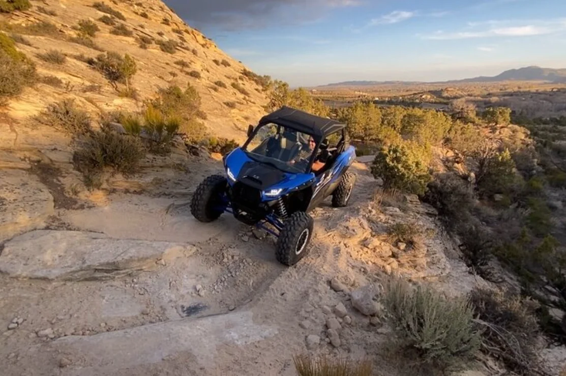 Side-by-side UTV climbing a slickrock ridge on a guided tour near Vernal Utah